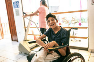 young boy with celebral palsy on a wheelchair smiling at the camera