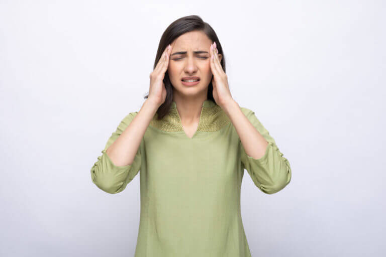 A picture depicting a young woman suffering from a severe headache.